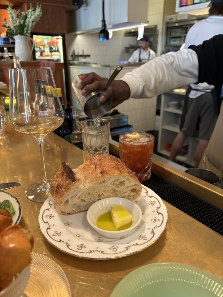 Our server mixes a cocktail in the background with sourdough from nearby Automne Boulangerie in the foreground